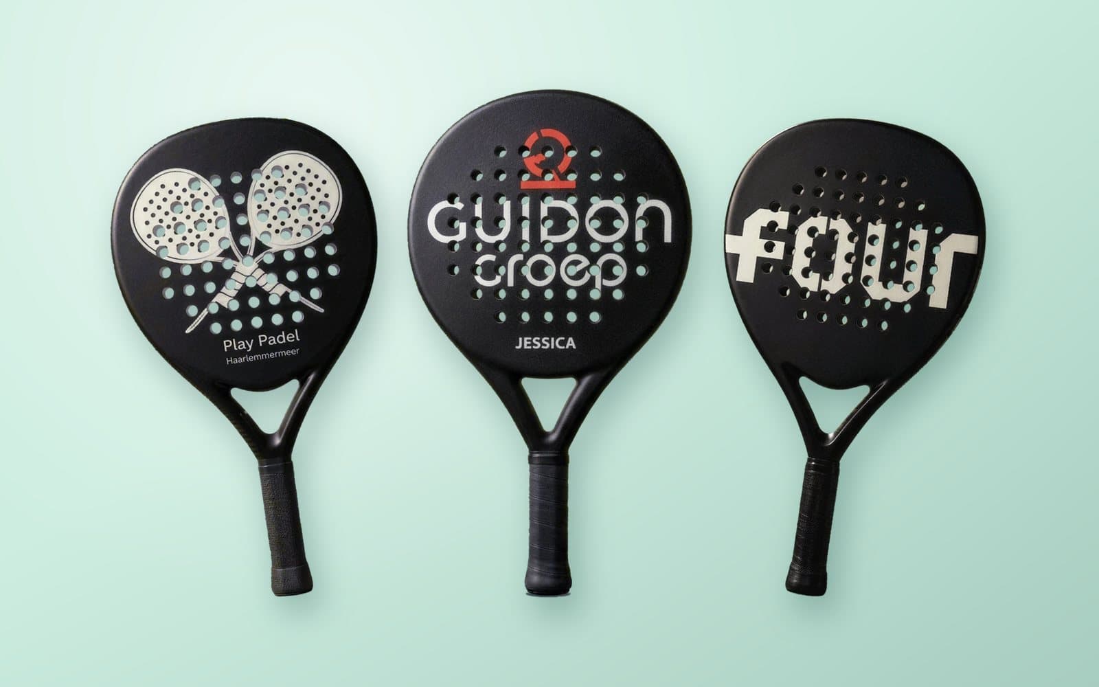 Three custom padel rackets with the logos of Play Padel, Guidon Groep and FOUR, on a mint green background