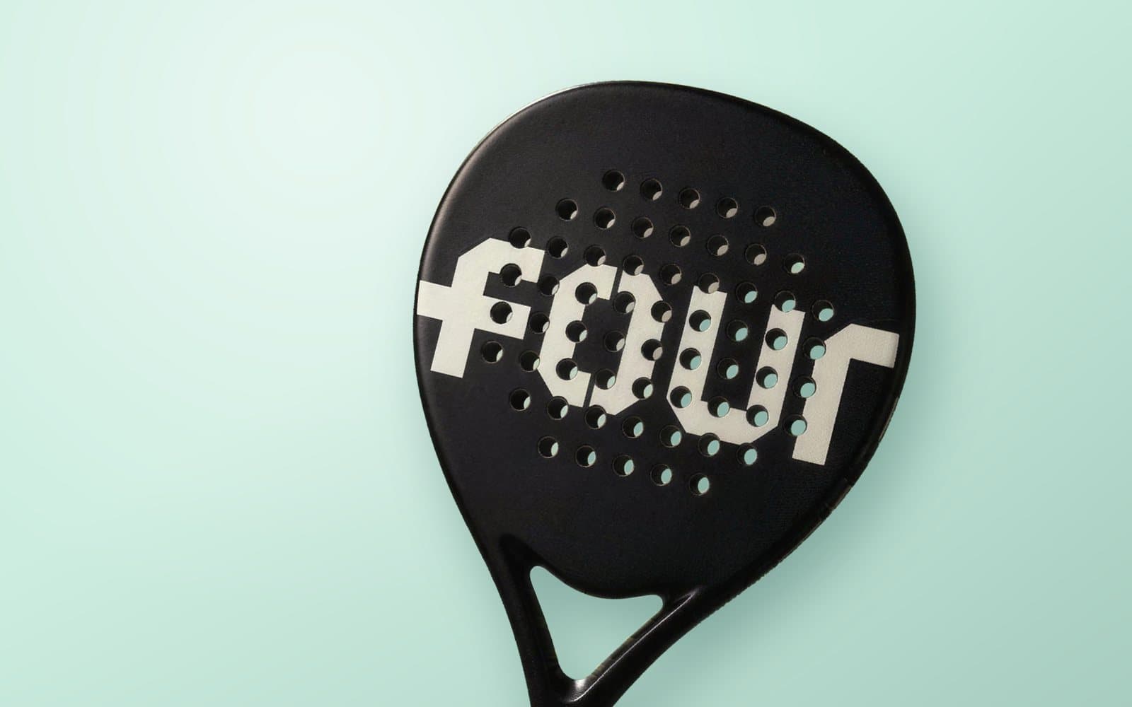 Black custom padel racket with the word FOUR in white on the face, on a mint green background