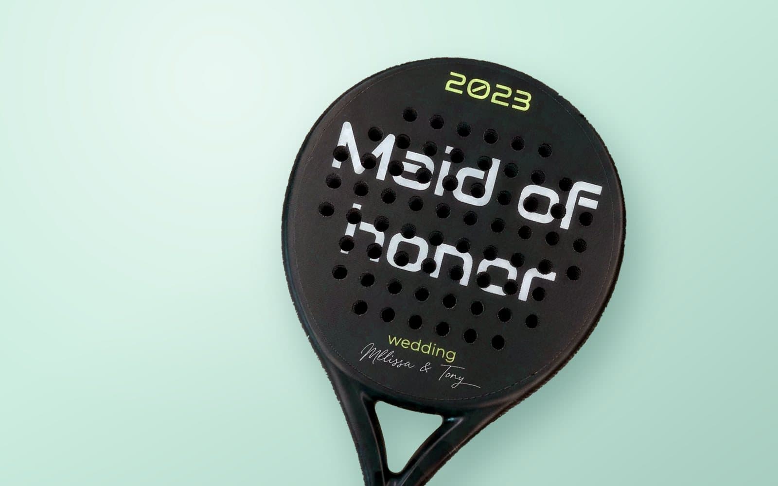 Custom padel racket reading Maid of honor, with the year 2023 and the couple's names, on a mint green background