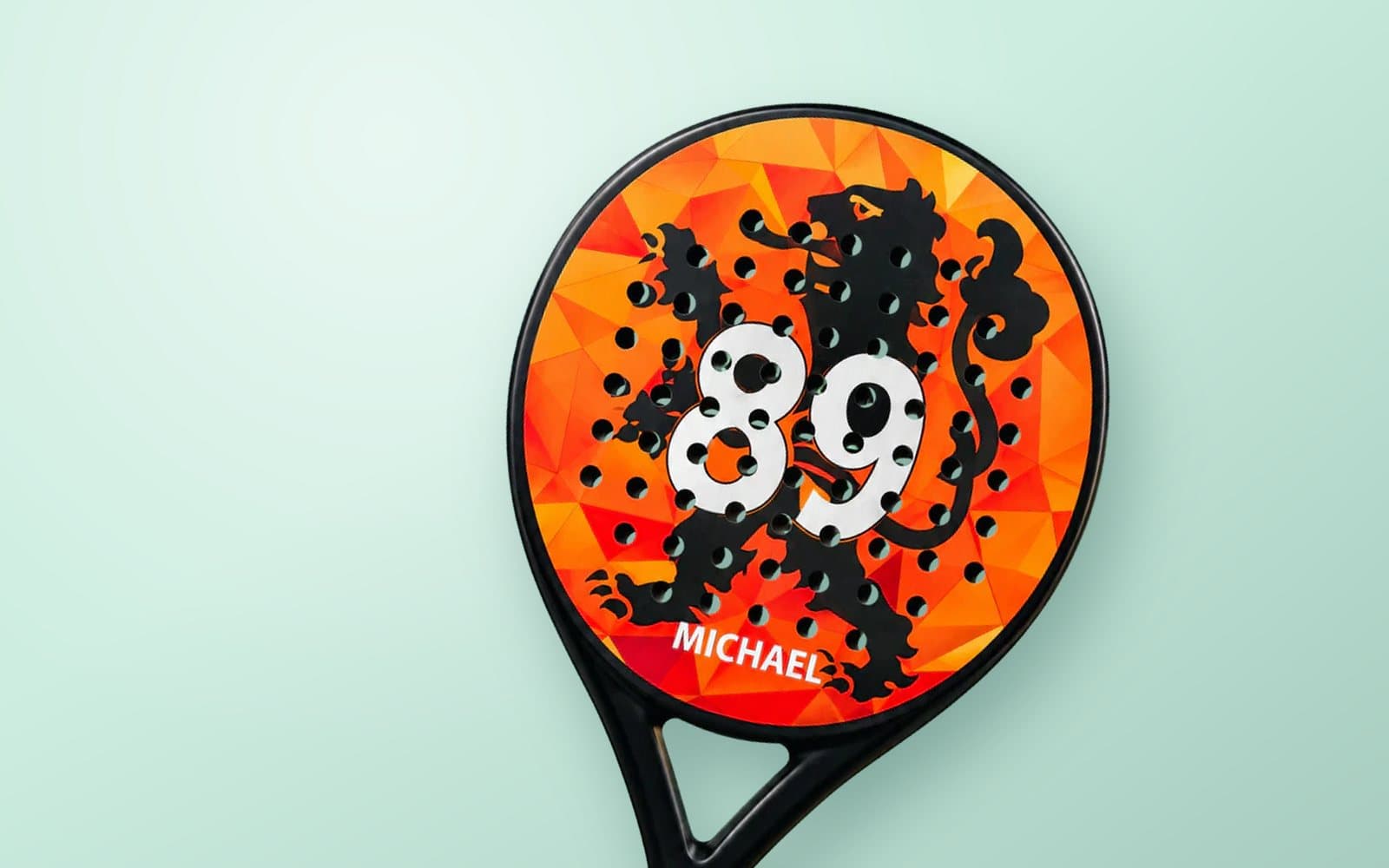 Custom padel racket met een oranje leeuwontwerp, rugnummer 89 en de naam MICHAEL, op een mintgroene achtergrond